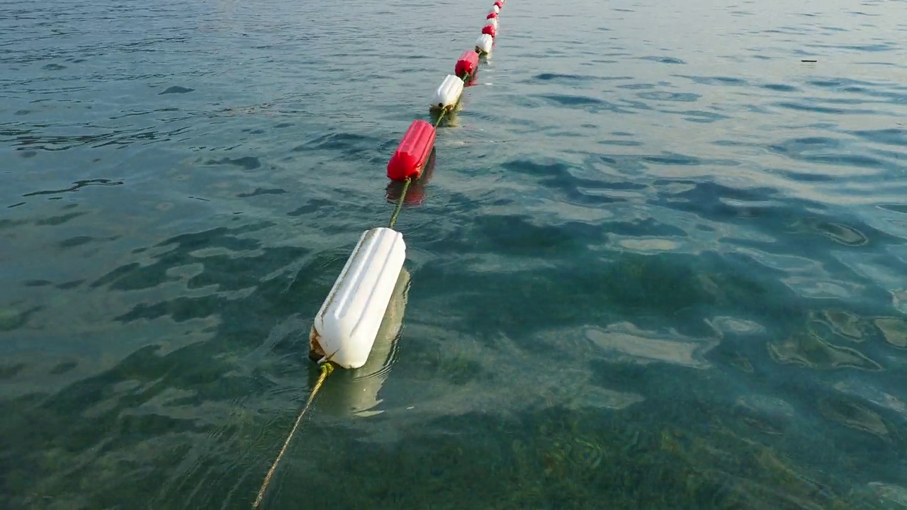 浮标游泳区域标记。可见的通道标记涂有耐用的白色和海洋红色搪瓷，以增加耐用性。组装屏障和游泳区域。黑山亚得里亚海，水上的浮标。视频素材