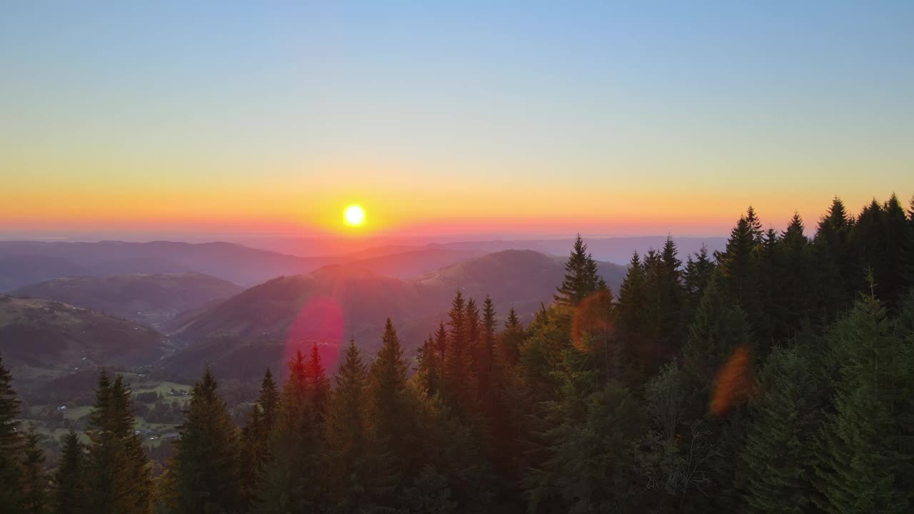 美丽的自然景观。鸟瞰山野中五彩缤纷的日落。黑暗的松林被明亮的夕阳照亮视频素材