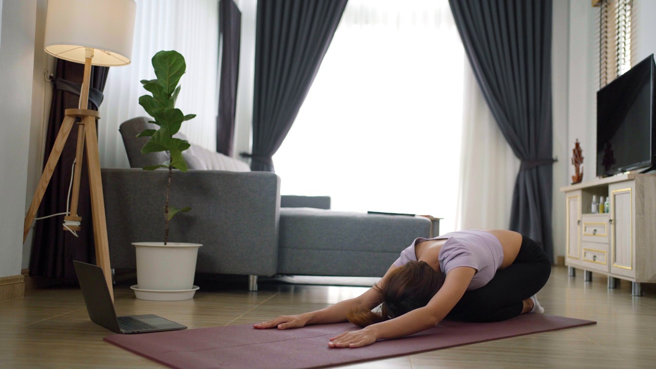 年轻的肌肉健身女性在家里客厅地板上的瑜伽垫上做运动和瑜伽视频素材