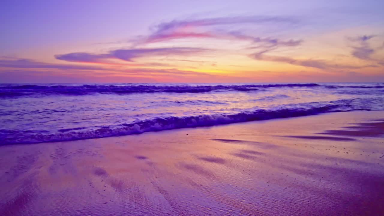 在日出或日落天空在海上的彩色海洋海滩，美丽的海浪冲击粉红色的沙滩在夏季，慢动作海浪海滩背景视频素材