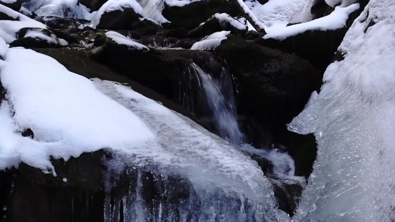 在冬天，从一条有冰雪的小溪中看到一点点结冰的水，这是一幅美妙的景色视频下载