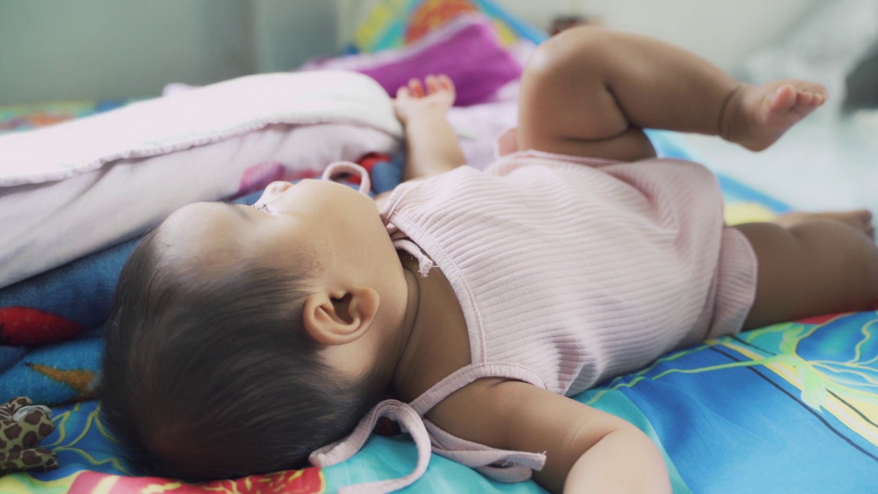 亚洲女孩婴儿玩爬行和幸福在她的床上。视频下载
