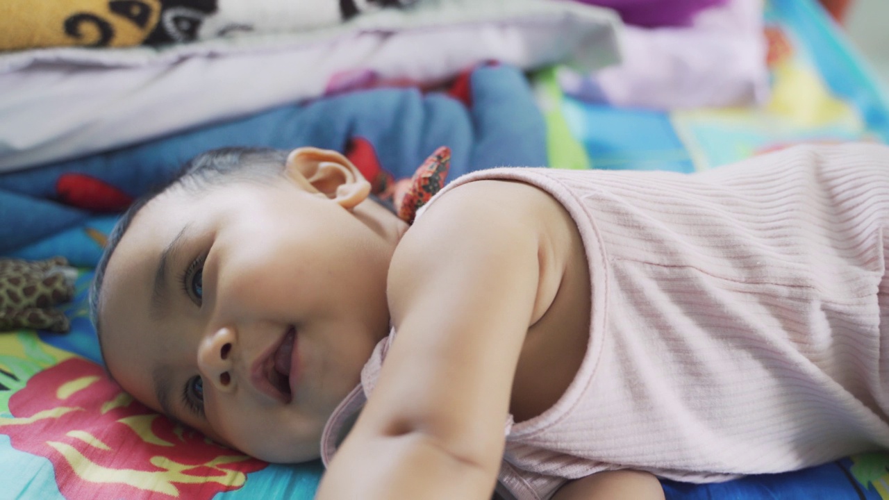 亚洲女孩婴儿玩爬行和幸福在她的床上。视频下载