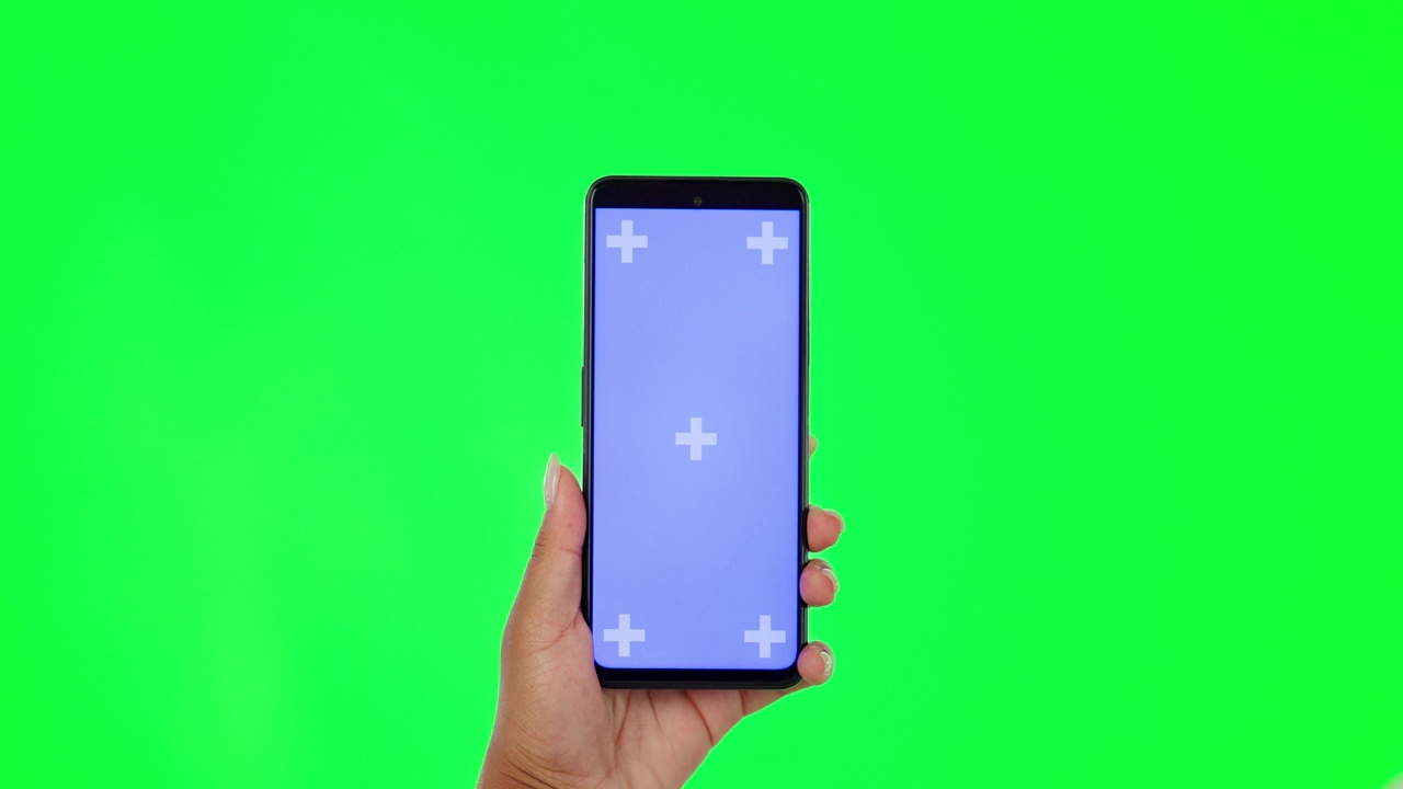 女人，手和手机在绿色屏幕上，在工作室背景的模型上做广告。女性手持带有广告跟踪标记的手机应用显示屏视频素材