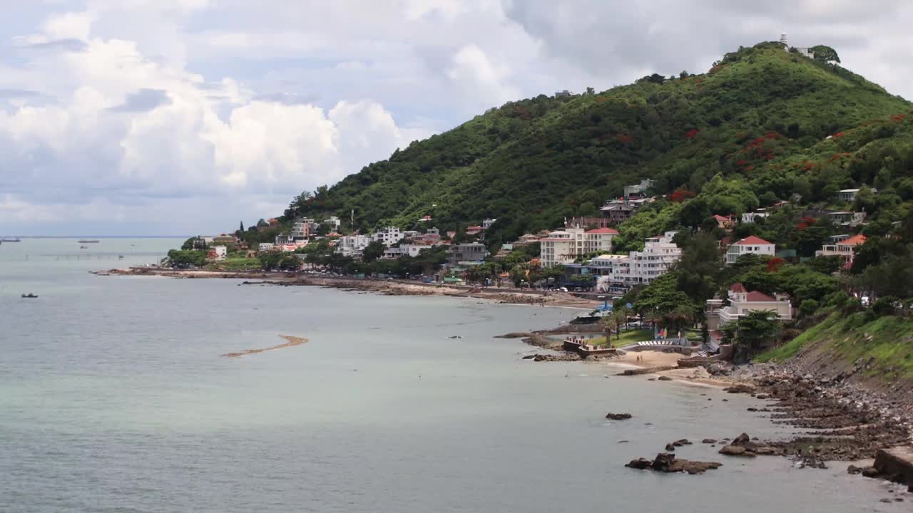 云头海滩的海岸线有蓝色的海洋。海浪涌来，游客们沿着海滩放松。视频下载