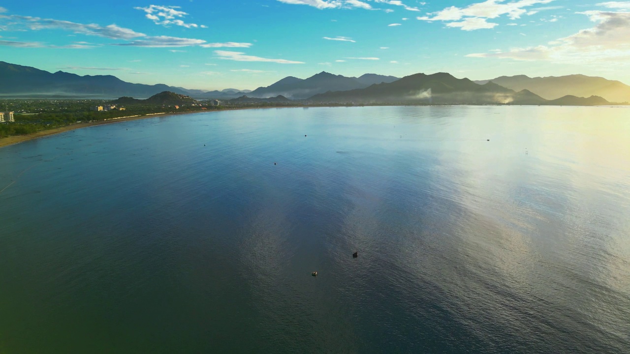 在一个晴朗的日子里，无人机在海滩上空飞行，蓝天，从高角度鸟瞰海浪和海水撞击沙滩的画面视频素材