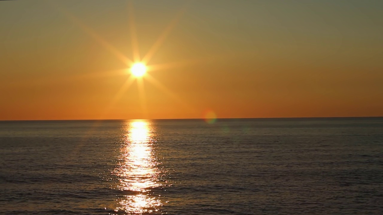 夕阳照在海面上，阳光闪耀着橘黄色视频素材