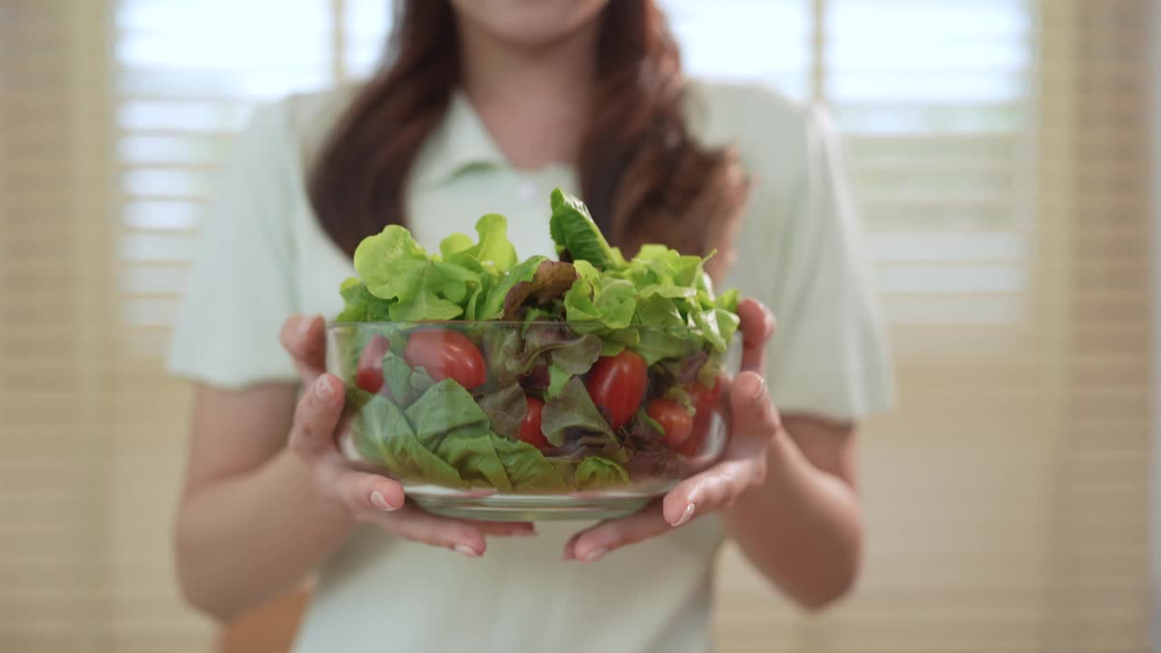 健康的年轻亚洲女性正在节食，在家吃沙拉。视频素材