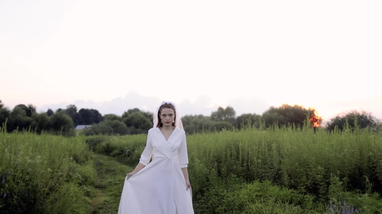 美丽的女模特在夕阳下穿过田野。自由和独立女性的概念视频素材