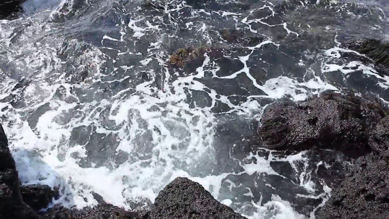 海浪在黑色玄武岩上打白的视频视频素材