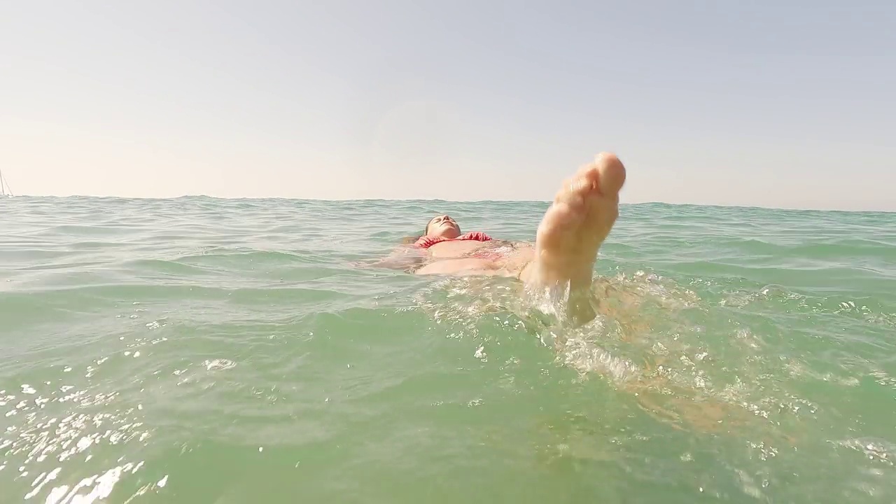 成熟的成年女子在夏季的海水中游泳。海滩和海岸概念视频素材