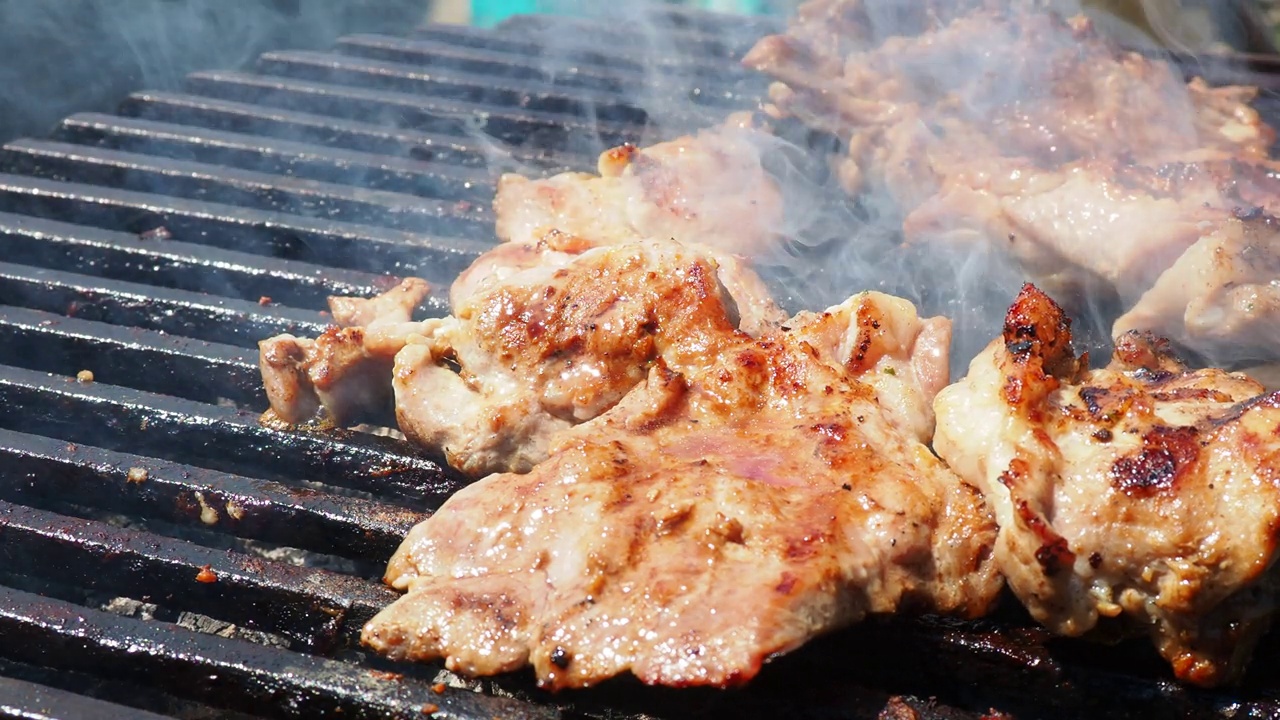 烤多汁的肉，猪肉牛排，在烧烤架上燃烧的煤，火焰和烟雾。多汁的条纹烤牛排为野餐庆典做好了准备。烧烤架。视频素材