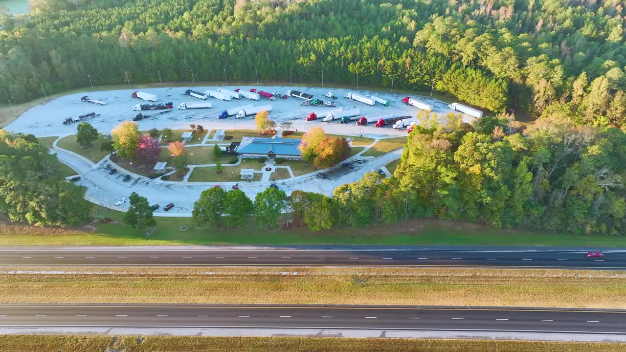 在繁忙的美国州际高速公路附近有休息区的大型卡车停靠站，有快速行驶的汽车和卡车。州际旅行期间的休闲停车场视频素材