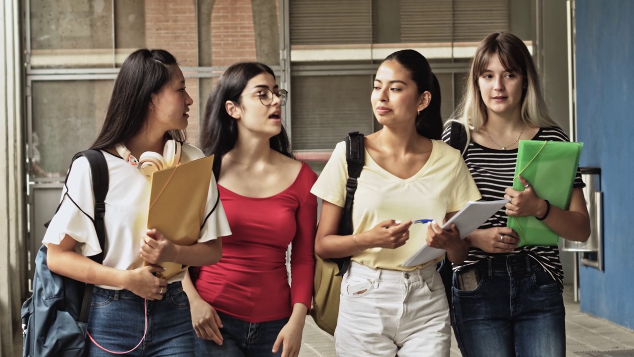 一群十几岁的女学生在校园里互相散步和交谈。高中，回到学校视频素材