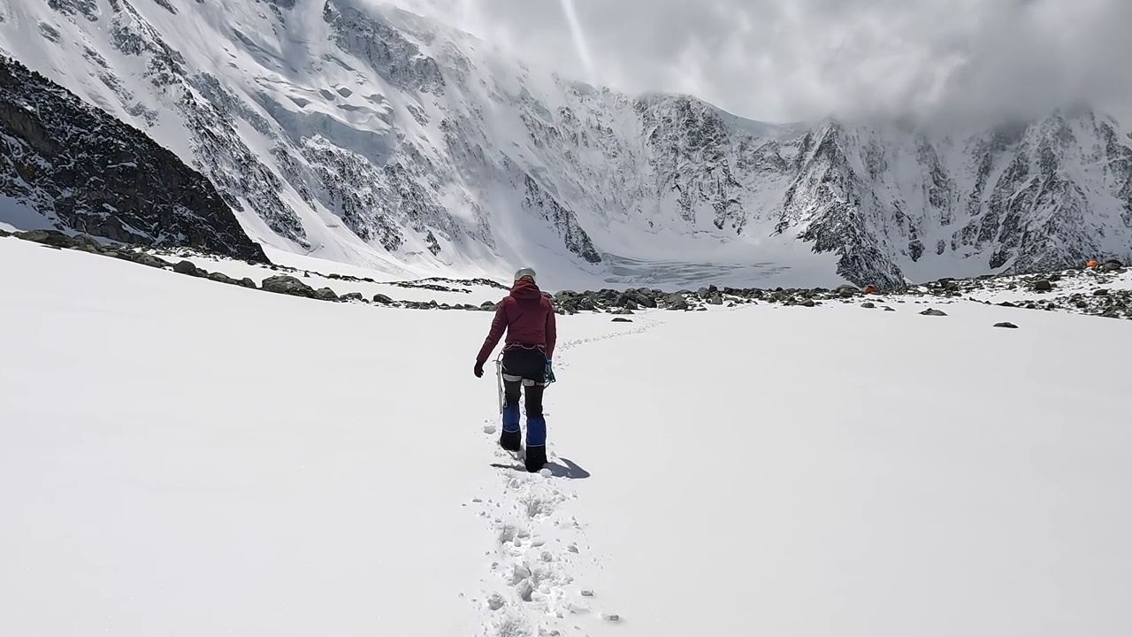 一位女登山者沿着雪道走在山上。攀登Belukha视频素材