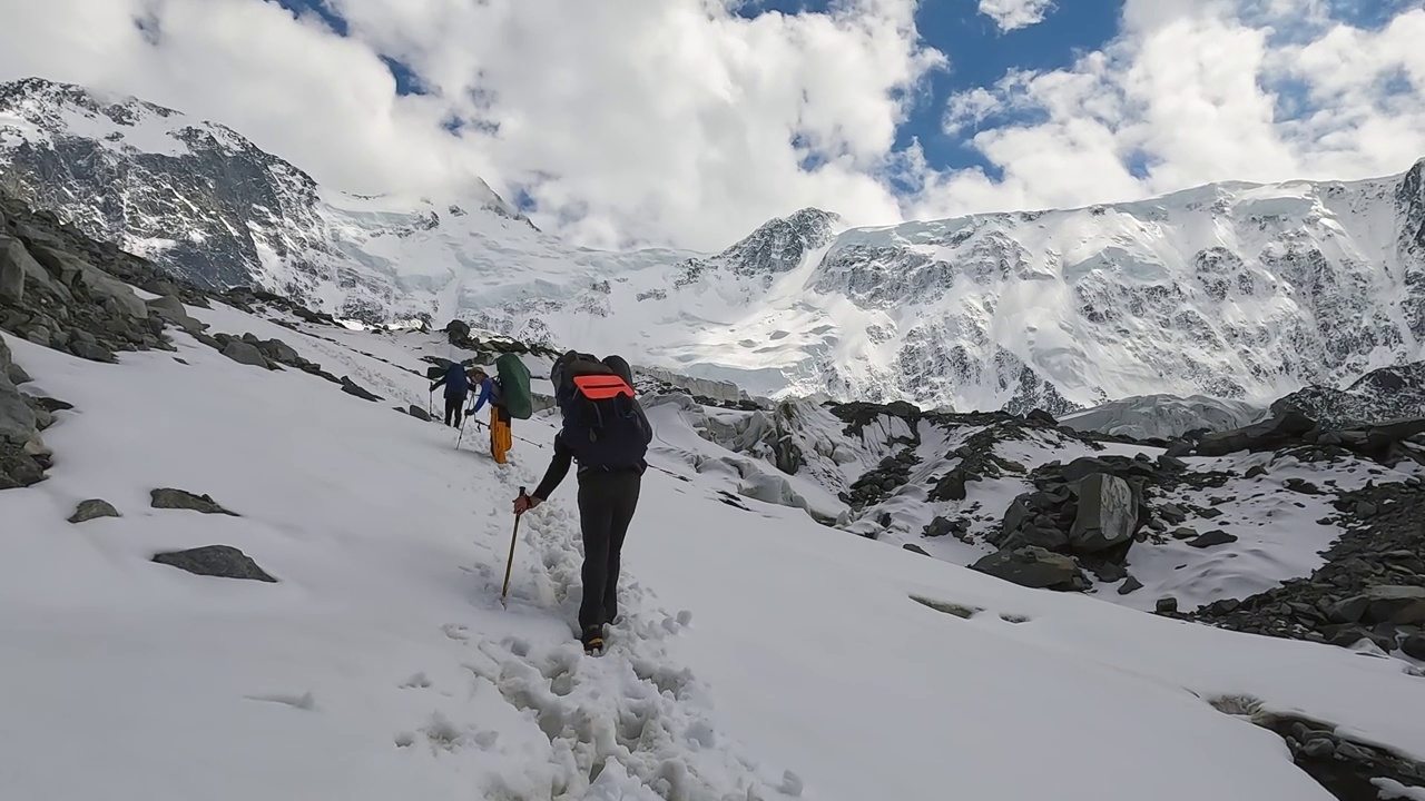 三名背着大背包的男性登山者正沿着雪道走在山上视频素材