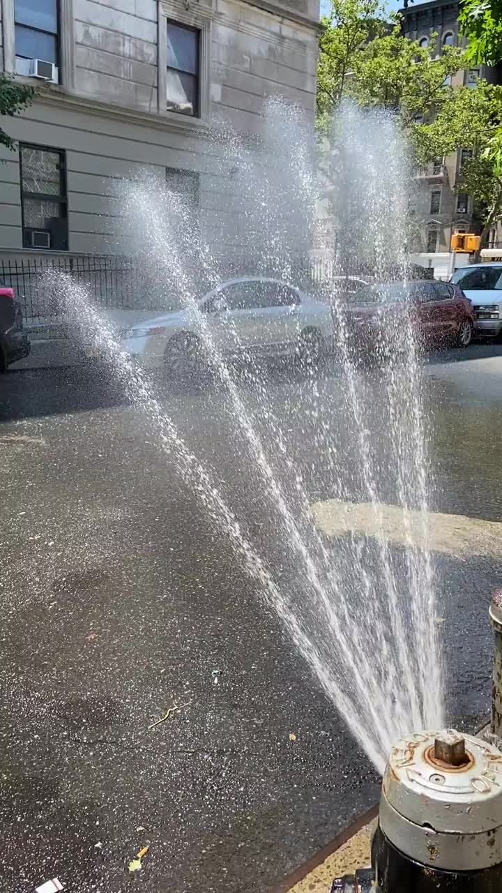 在纽约炎热的夏日，带喷头的消防栓向街道喷水视频下载