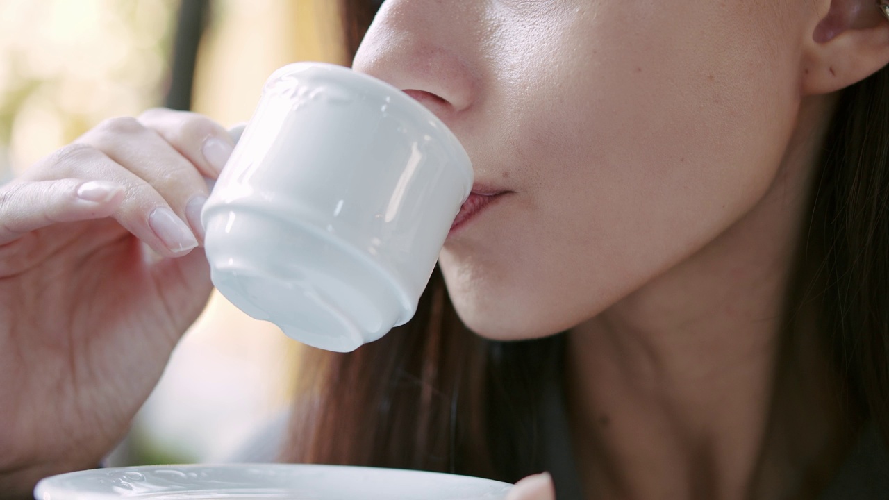 年轻女子在街上喝咖啡。视频素材