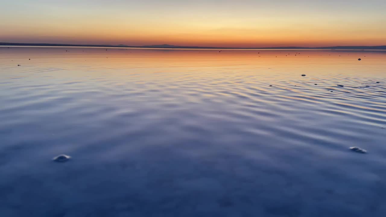 日落时，风吹在盐湖上形成的小波浪。视频下载