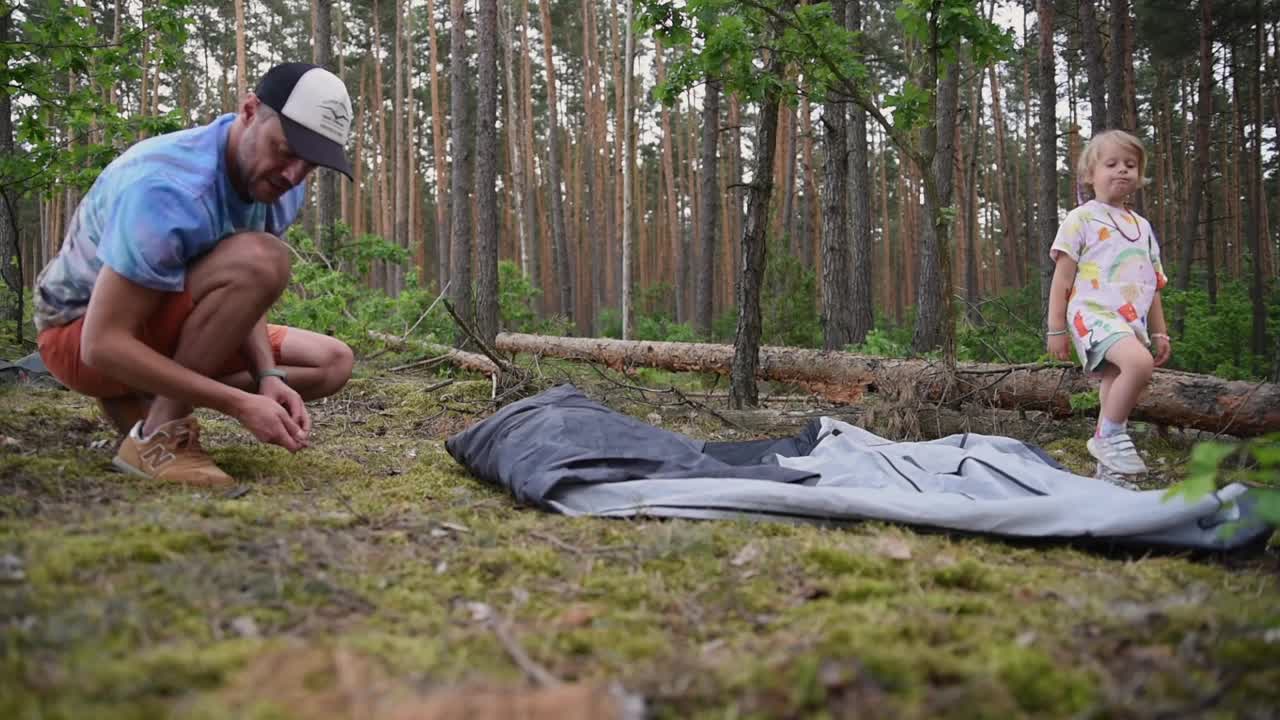 露营地搭建:清理地上的松果，搭建帐篷视频素材