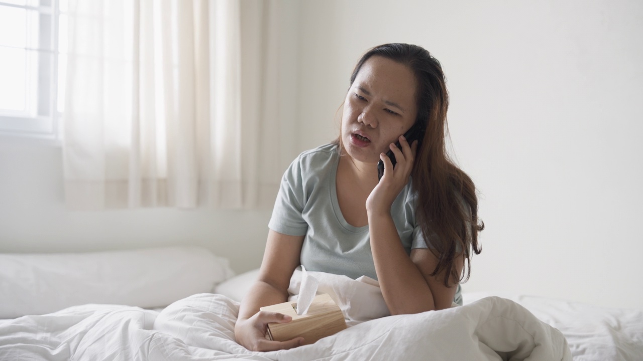 生病的女人在床上玩手机视频素材