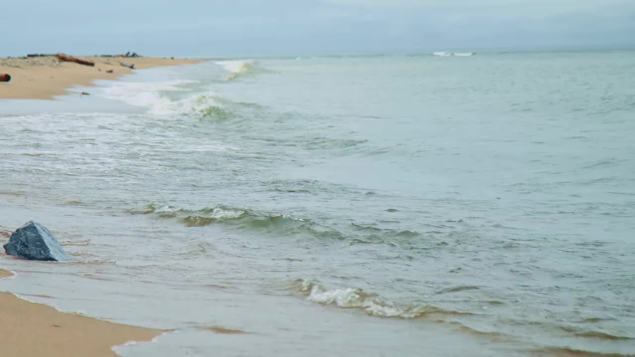 透明的海浪向海岸的运动。海浪平静地冲刷着沙滩的特写。美丽的风景放松。平静，冥想，放松的概念。视频素材