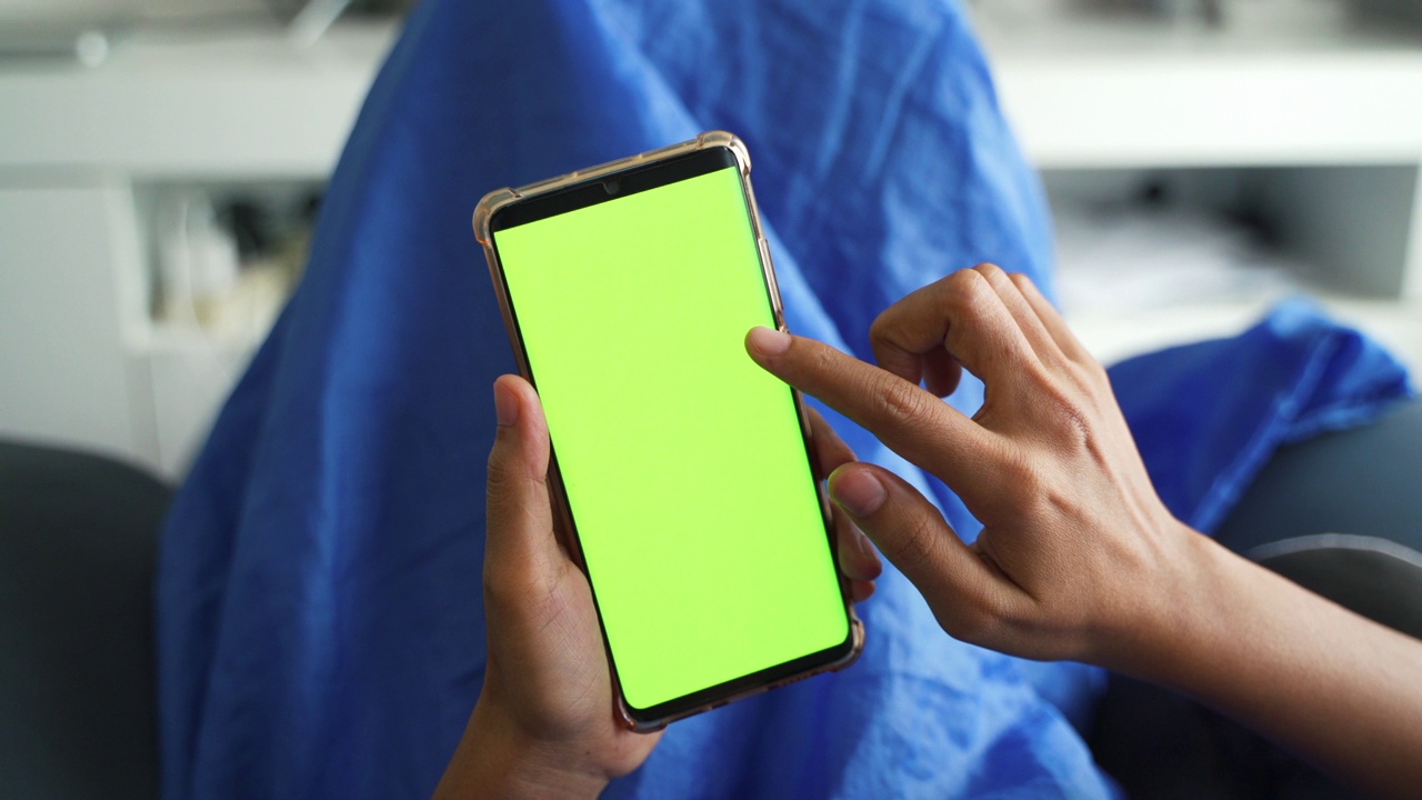 特写女性手持和使用带有色度键屏幕的智能手机。视频下载