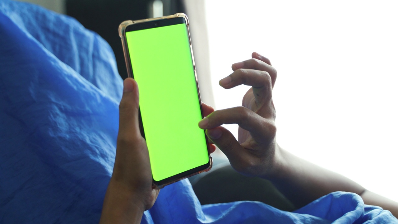 特写女性手持和使用带有色度键屏幕的智能手机。视频下载