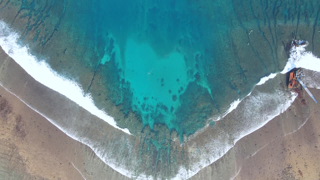 鸟瞰海浪到达热带海滩景观与废弃的海上施工起重机在努沙伦邦根岛，靠近巴厘岛，印度尼西亚视频素材