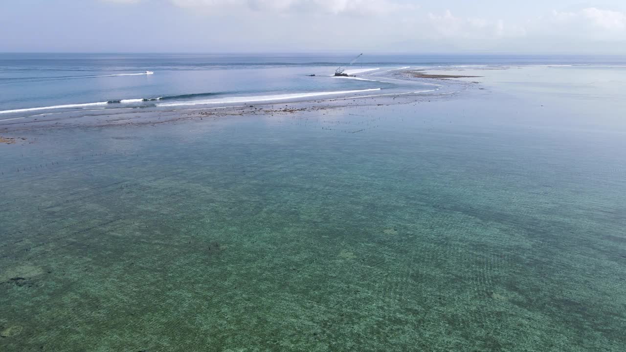 鸟瞰海浪到达热带海滩景观与废弃的海上施工起重机在努沙伦邦根岛，靠近巴厘岛，印度尼西亚视频素材