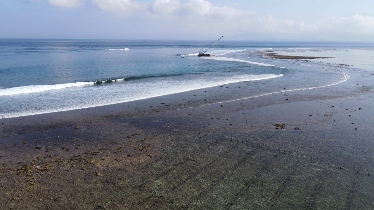 鸟瞰海浪到达热带海滩景观与废弃的海上施工起重机在努沙伦邦根岛，靠近巴厘岛，印度尼西亚视频素材