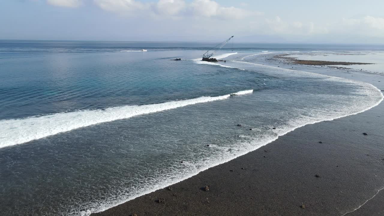 鸟瞰海浪到达热带海滩景观与废弃的海上施工起重机在努沙伦邦根岛，靠近巴厘岛，印度尼西亚视频素材