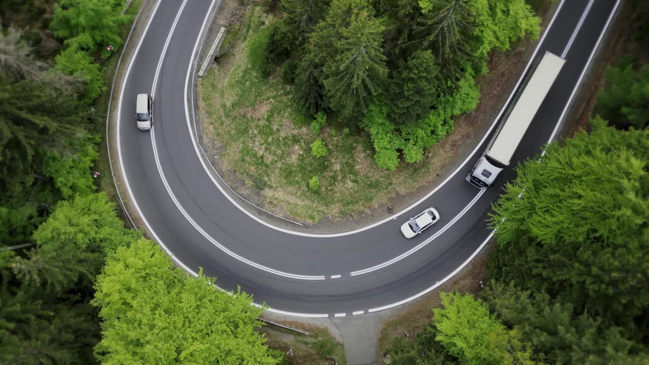 鸟瞰卡车和拖车行驶在美丽的乡村森林公路在山区。一个乡村公路的急转弯和一辆半挂车的卡车。海运、送货、运输。视频素材