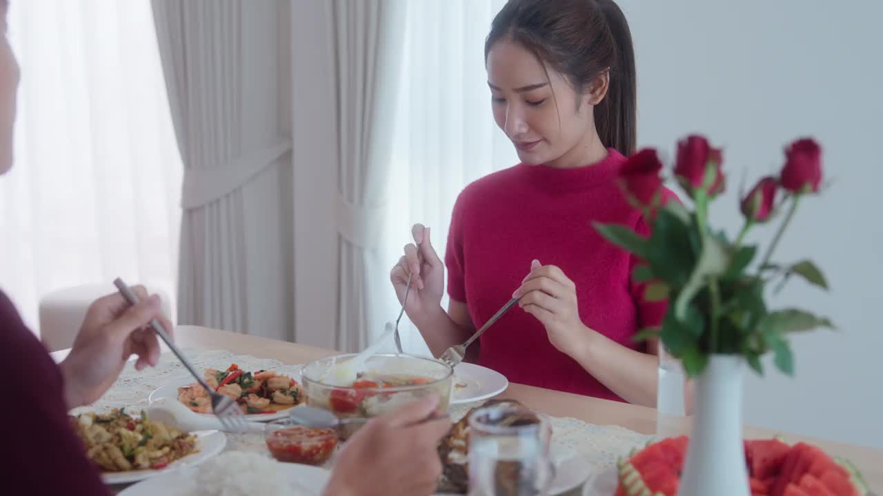 年轻的亚洲夫妇在家里的桌子上吃着食物，轮流喂对方。视频素材