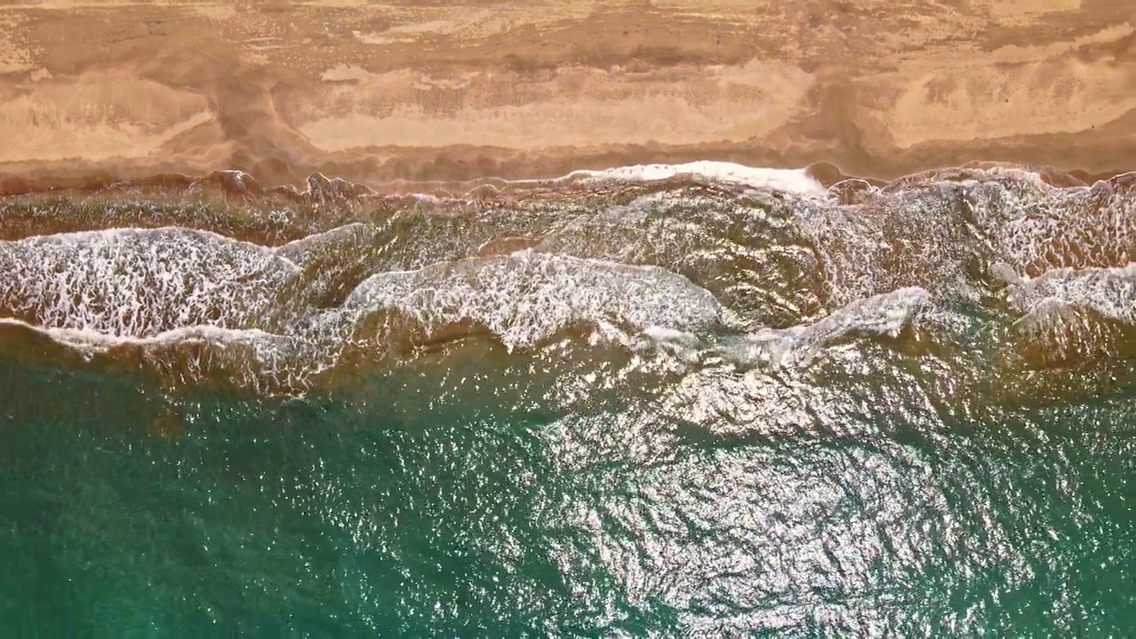 海浪或海浪。泡沫滚滚的海浪拍打着沙滩。空中俯瞰，4K。视频素材