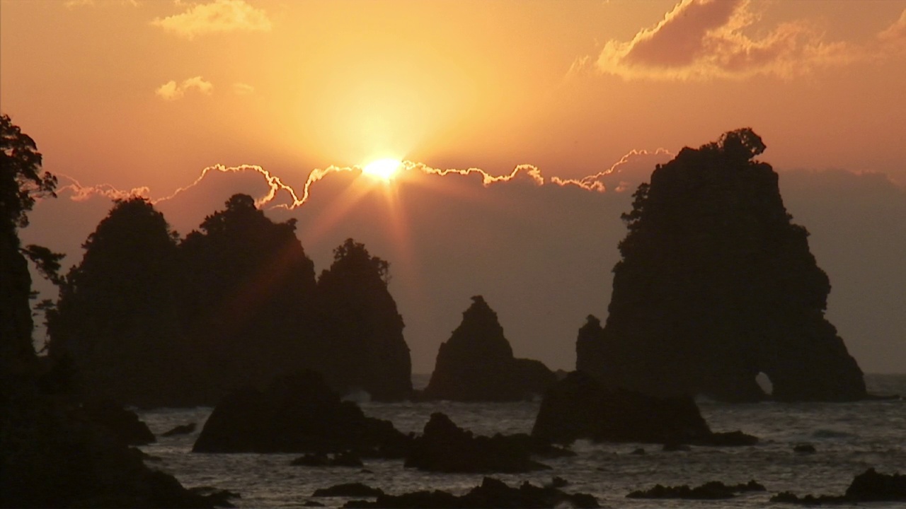 海洋岩层的剪影映衬着明亮的天空视频素材