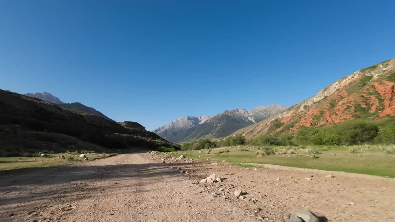 驾车穿过美丽的山峡，一边是红色的岩石，前面是山峰。汽车的观点视频素材