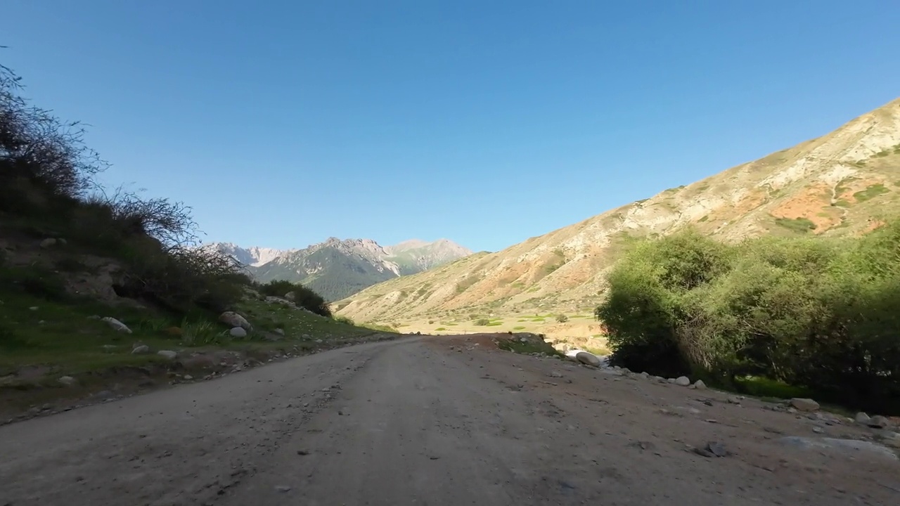 驾车穿过美丽的山峡，一边是红色的岩石，前面是山峰。汽车的观点视频素材