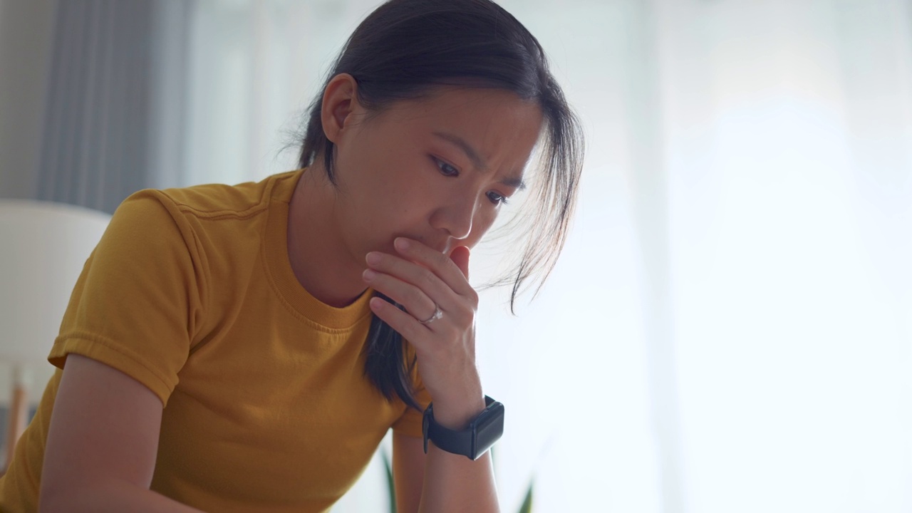 亚洲女性坐在沙发上，担心银行票据、抵押贷款债务和生活成本的账单支付问题。视频素材