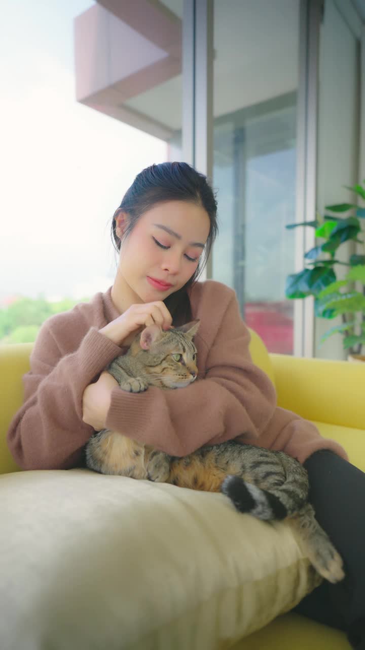 漂亮的亚洲女人和她的猫躺在沙发上。视频素材