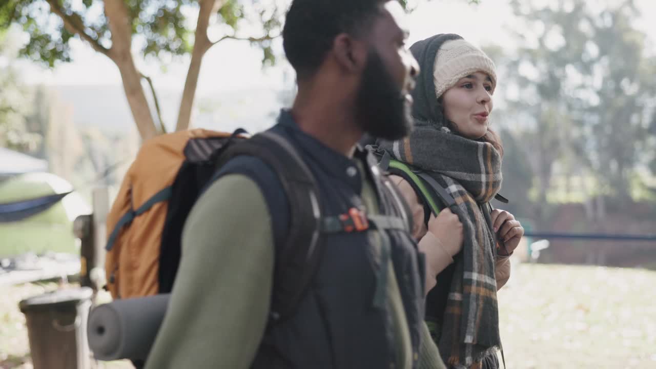 跨种族情侣，从露营地出发，背着背包在大自然中徒步旅行，一起度假或冒险。快乐的男人和女人聊天，徒步旅行和享受露营假期或周末在外面视频素材