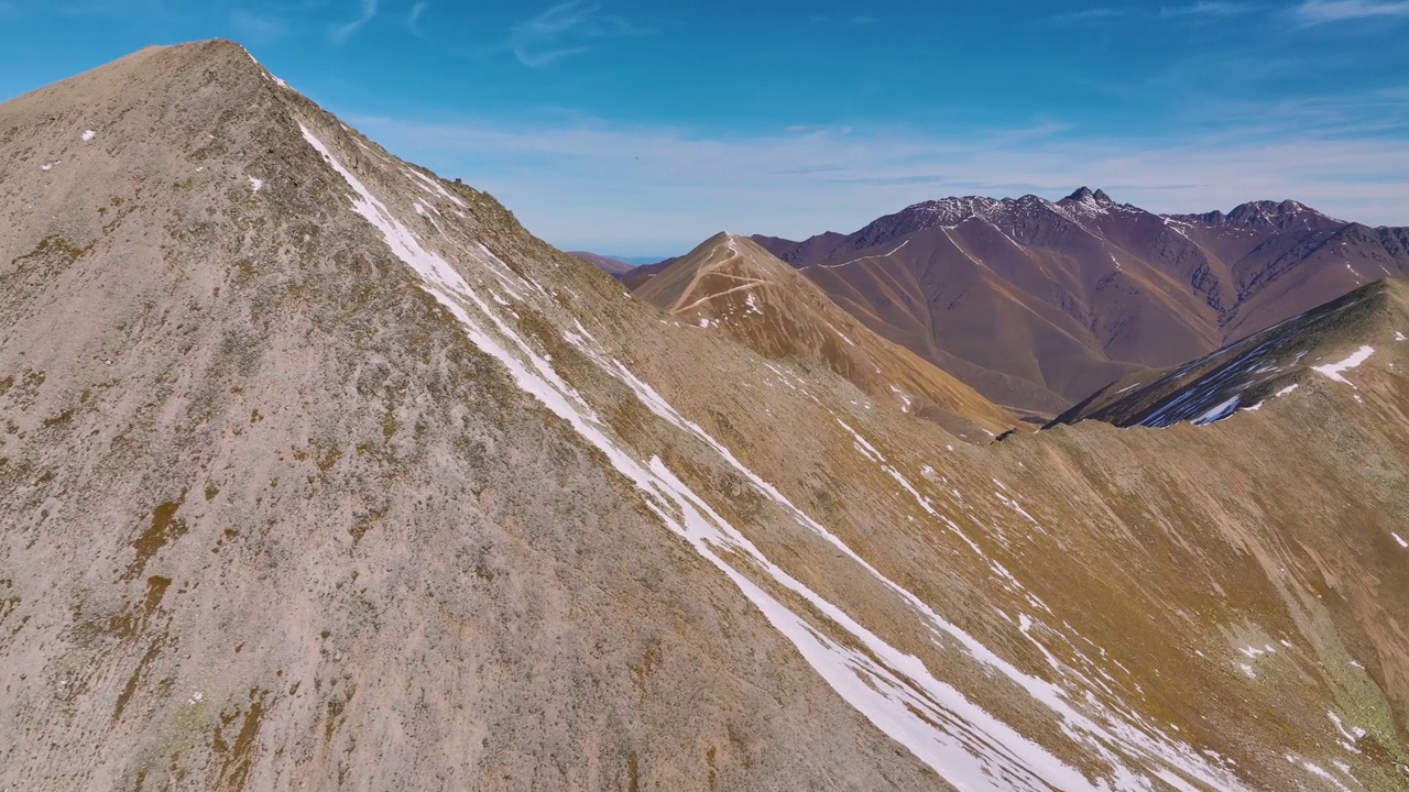 夏季雪山鸟瞰图。山里阳光明媚的一天。山脉顶部的岩石。在无人的高山上航拍视频素材