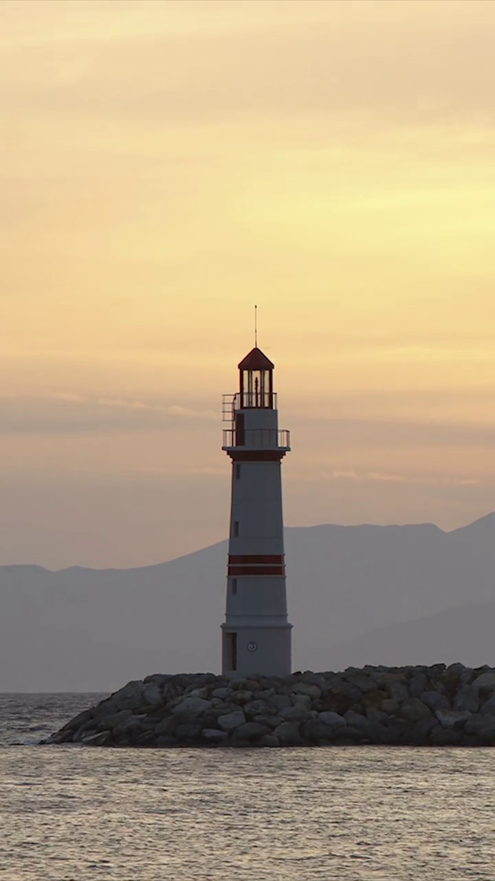 日落时的海景。海岸上的灯塔。海滨小镇Turgutreis和壮观的日落。社交媒体的垂直视频。视频素材