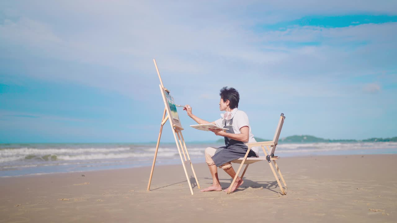 退休的老妇人在海边休息，用水彩画。假期在海滩上放松。视频素材