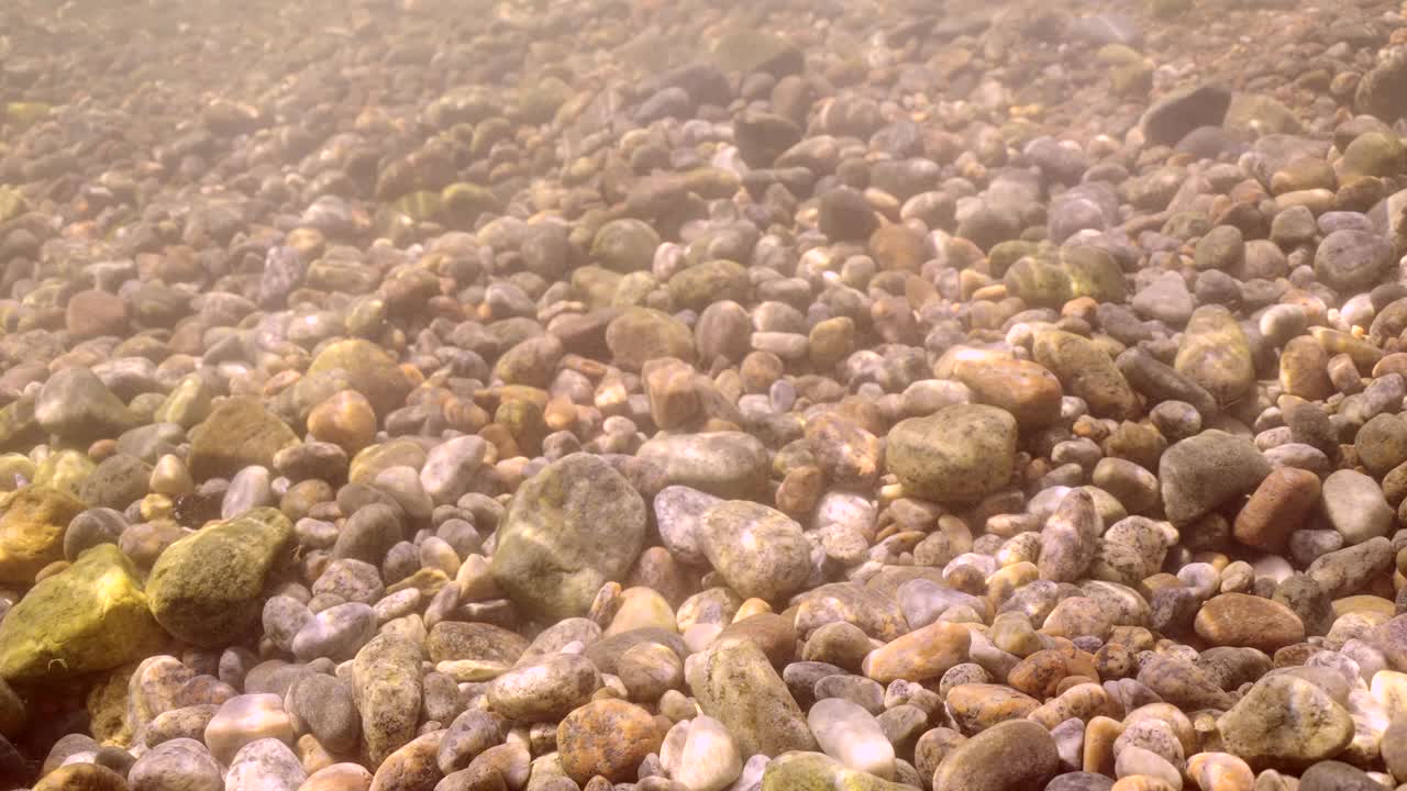 近景的海岸水下海景与卵石底在阳光的眩光视频素材