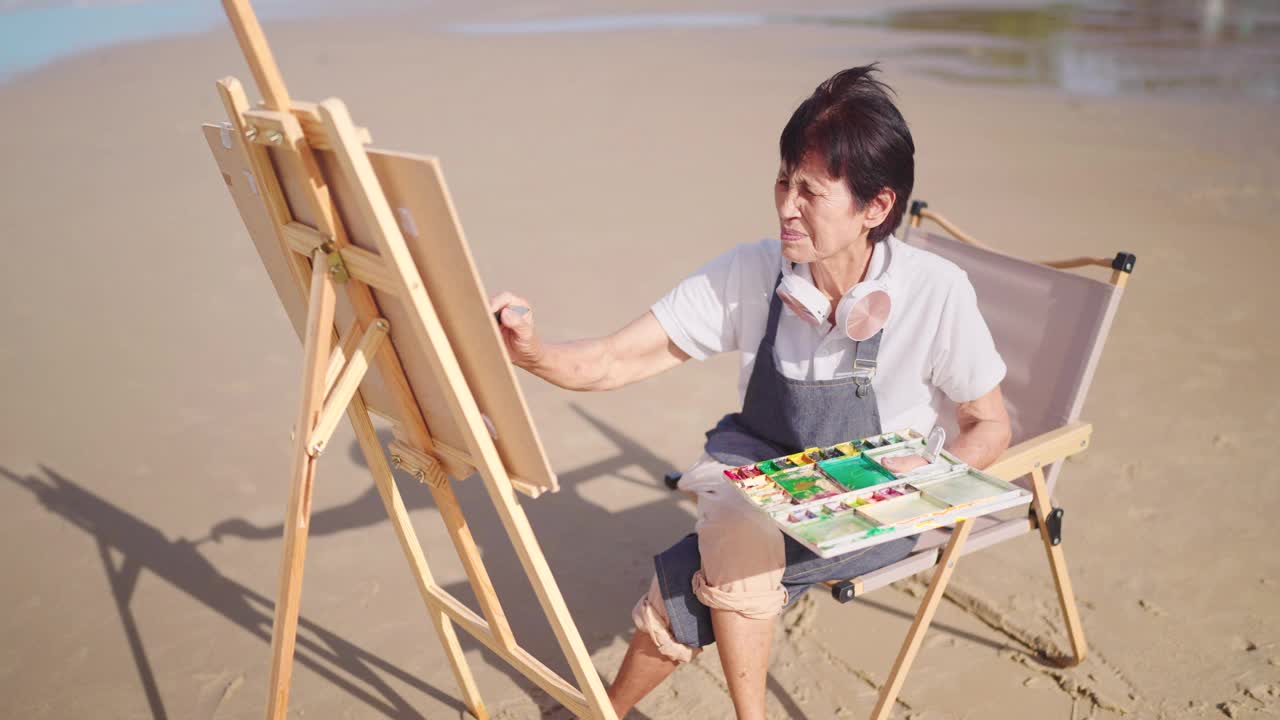 退休的老妇人在海边休息，用水彩画。假期在海滩上放松。视频素材