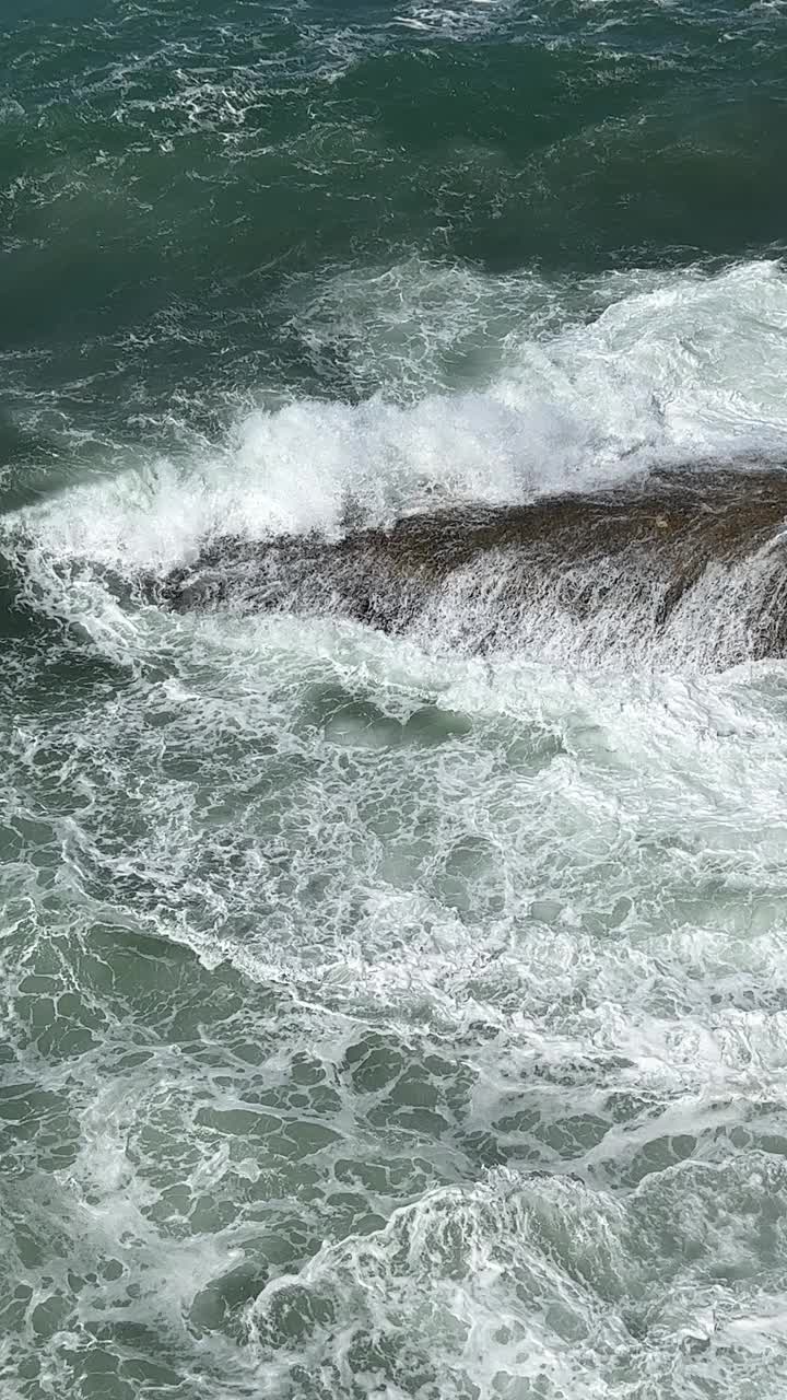 海浪拍打岩石，垂直视频。视频素材