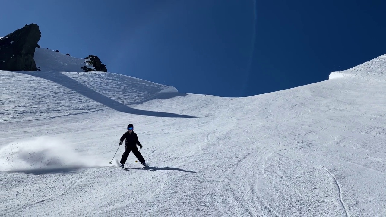 一个十几岁的滑雪者在蓝鸟的天气里从陡峭的山坡上下来视频下载