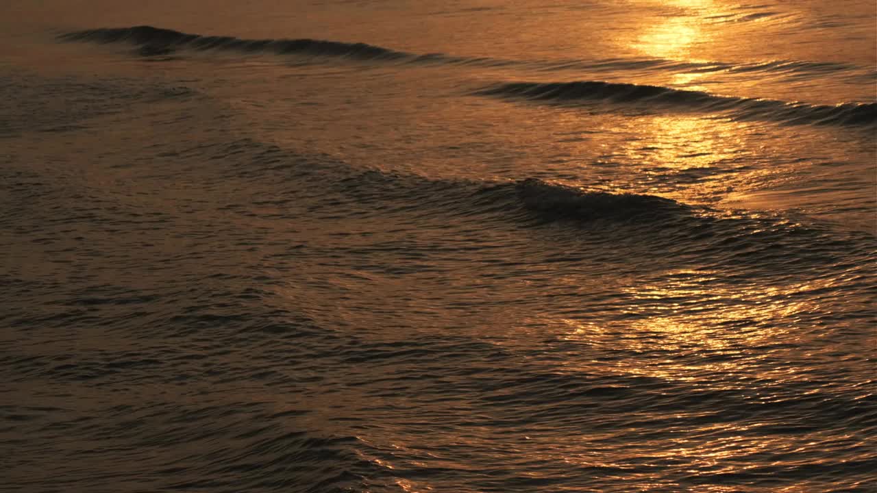 在日出或日落的热带海滩上，波浪飞溅。视频素材