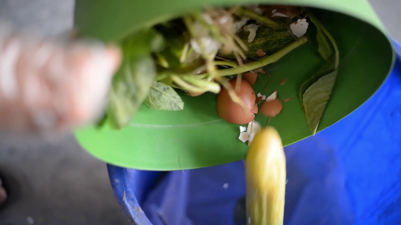 亚洲妇女在家里把剩饭剩菜或垃圾刮进厨房垃圾桶的特写视频素材